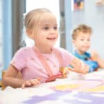 A preschool student smiles at a desk