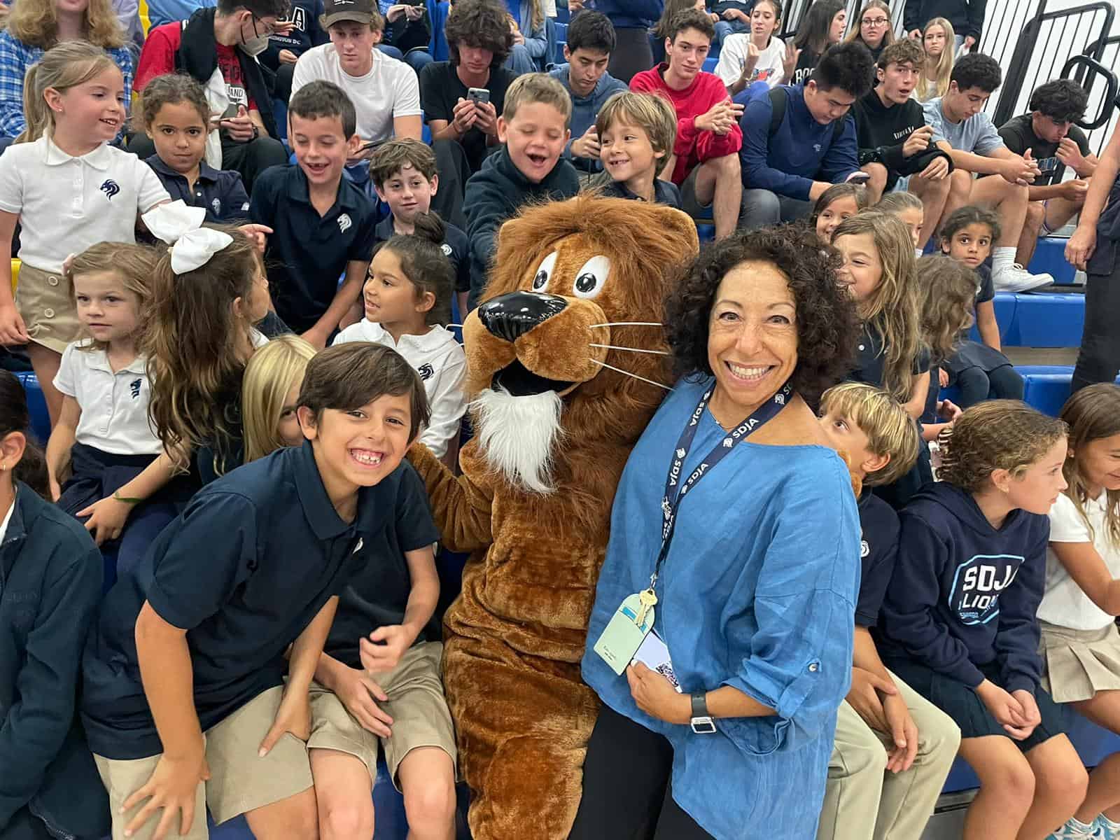 SDJA students and teacher with school mascot in the gym during an event.