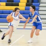 A girl dribbling a basketball past a defender during an SDJA girls basketball game.