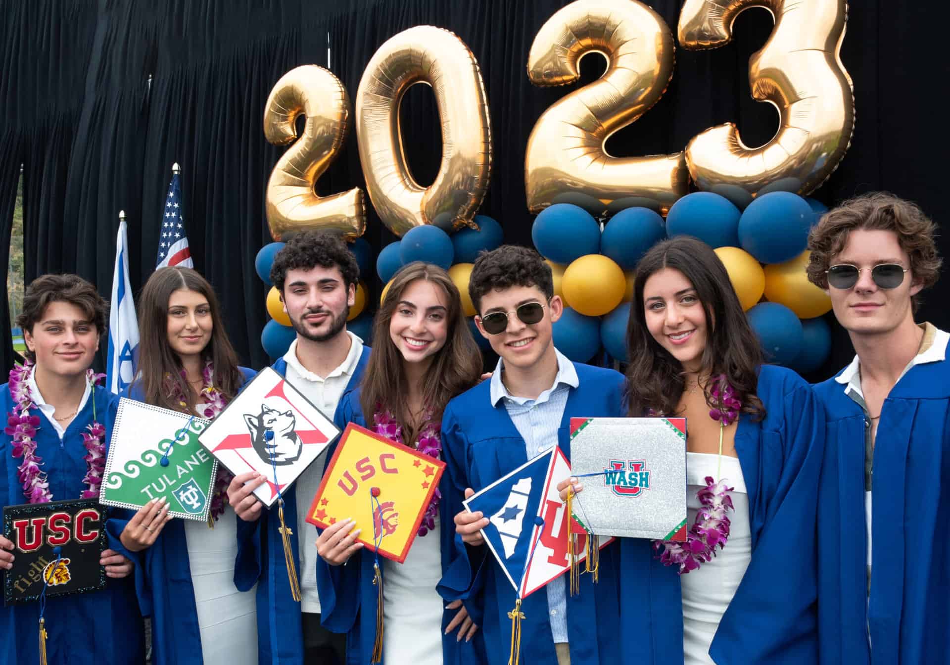 Upper school students pose on graduation stage with their caps