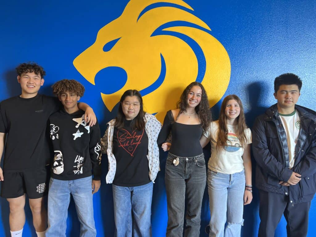 SDJA International students pose next to the lion mascot