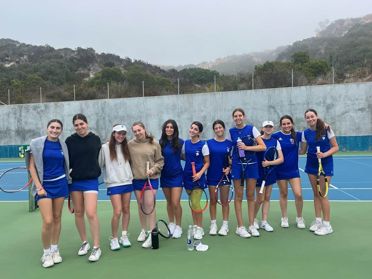 SDJA girls tennis team poses on the court for a team photo.