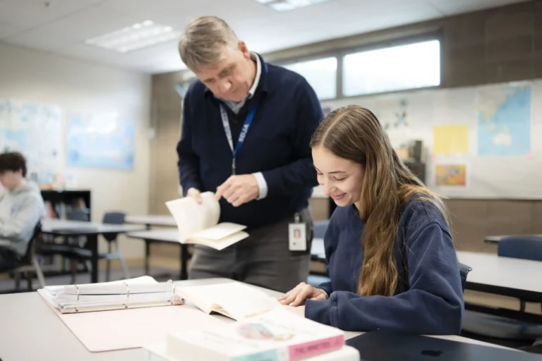 A teacher works closely with a student during class.