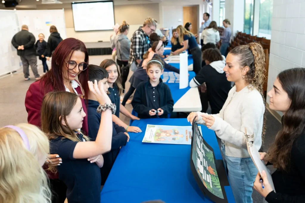 SDJA students congregate around a table while talking with a teacher