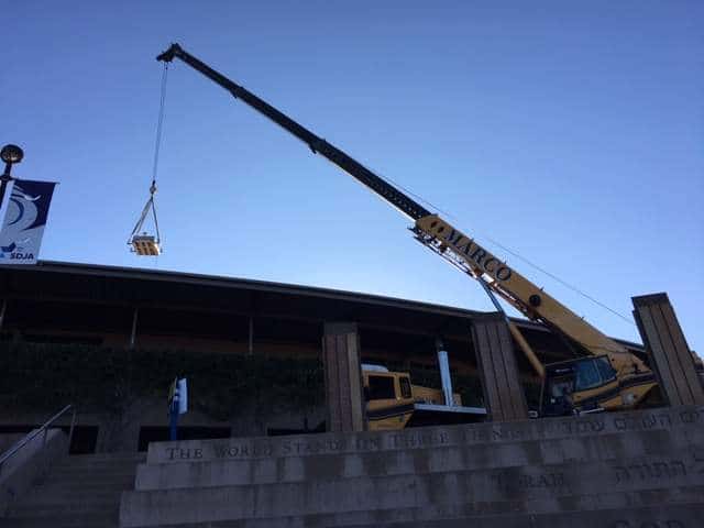 A crane lifts solar panels on to the roof of an SDJA building