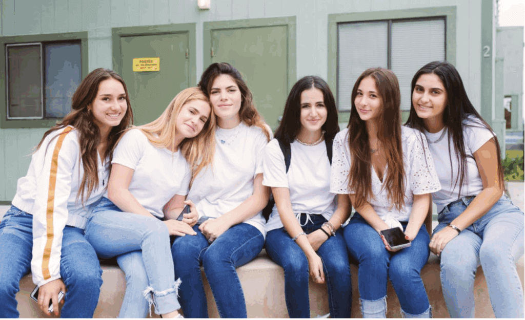SDJA students sit on a wall in front of classrooms on campus