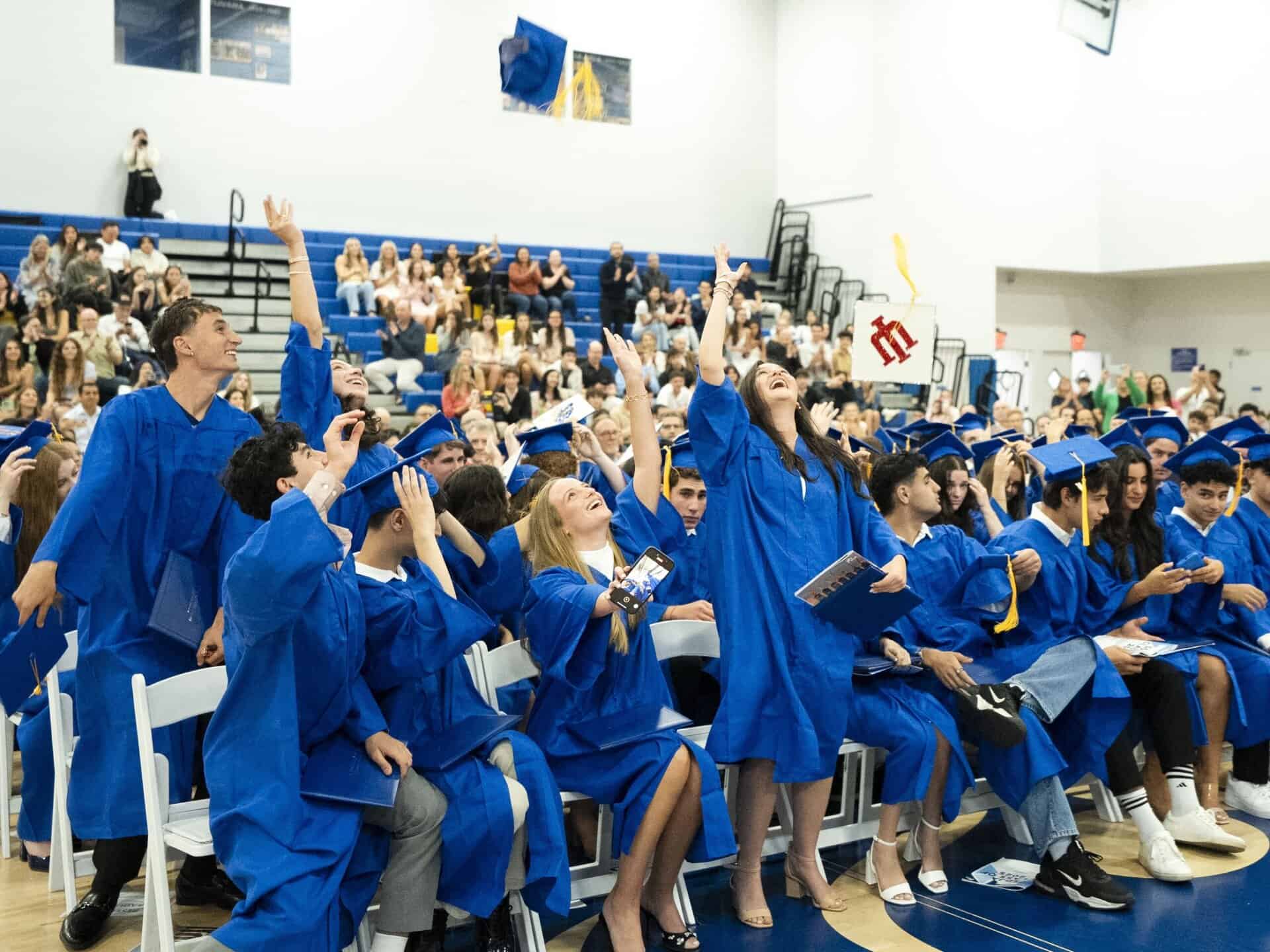 Students from SDJA 2025 graduating class toss their caps in the air at the conclusion of the graduation ceremony