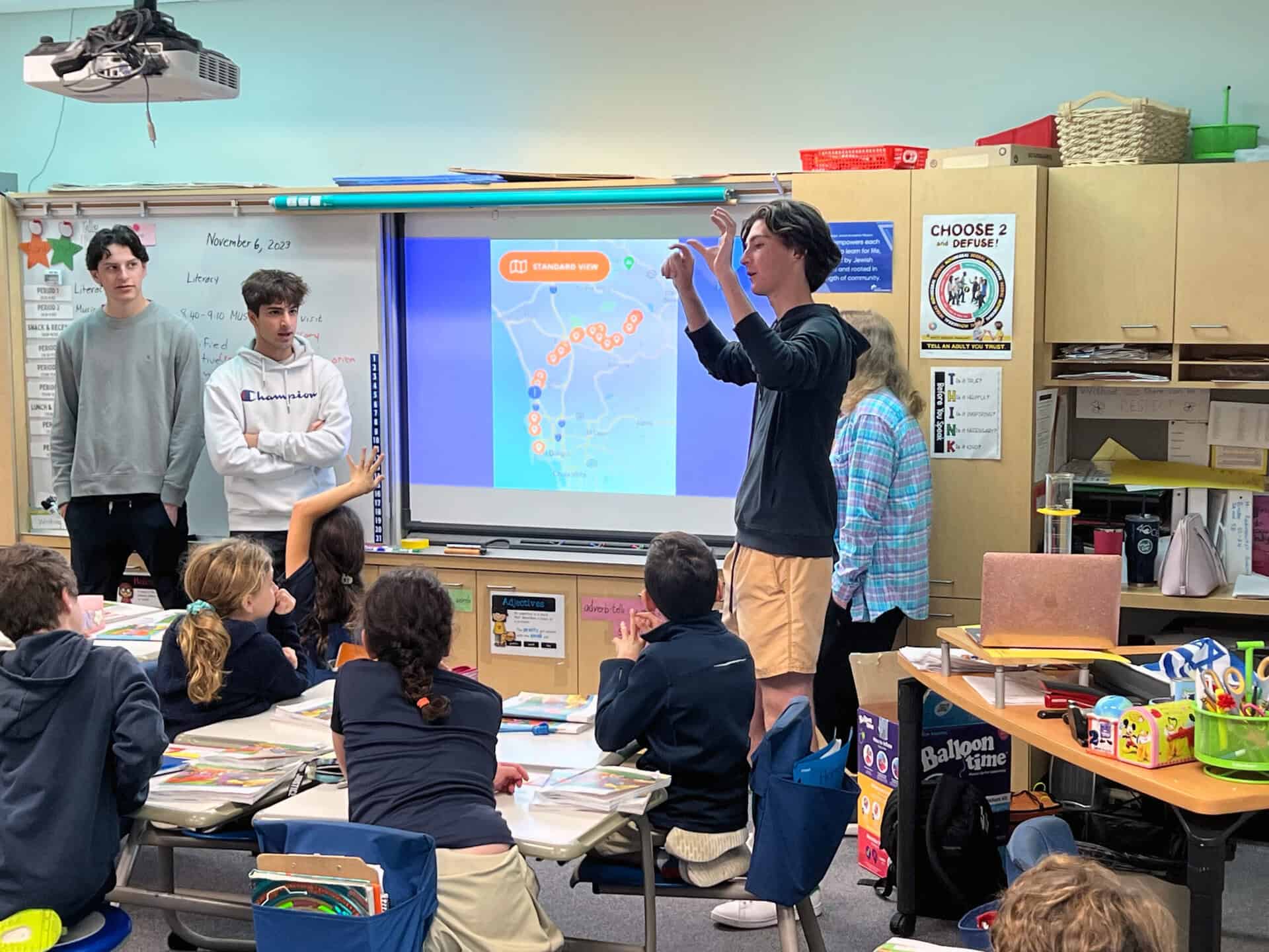 High school students teaching elementary school students about science and technology in a classroom.