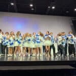 Students on stage during a performance with Israeli flags