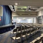 An auditorium with a stage and chairs on the SDJA campus