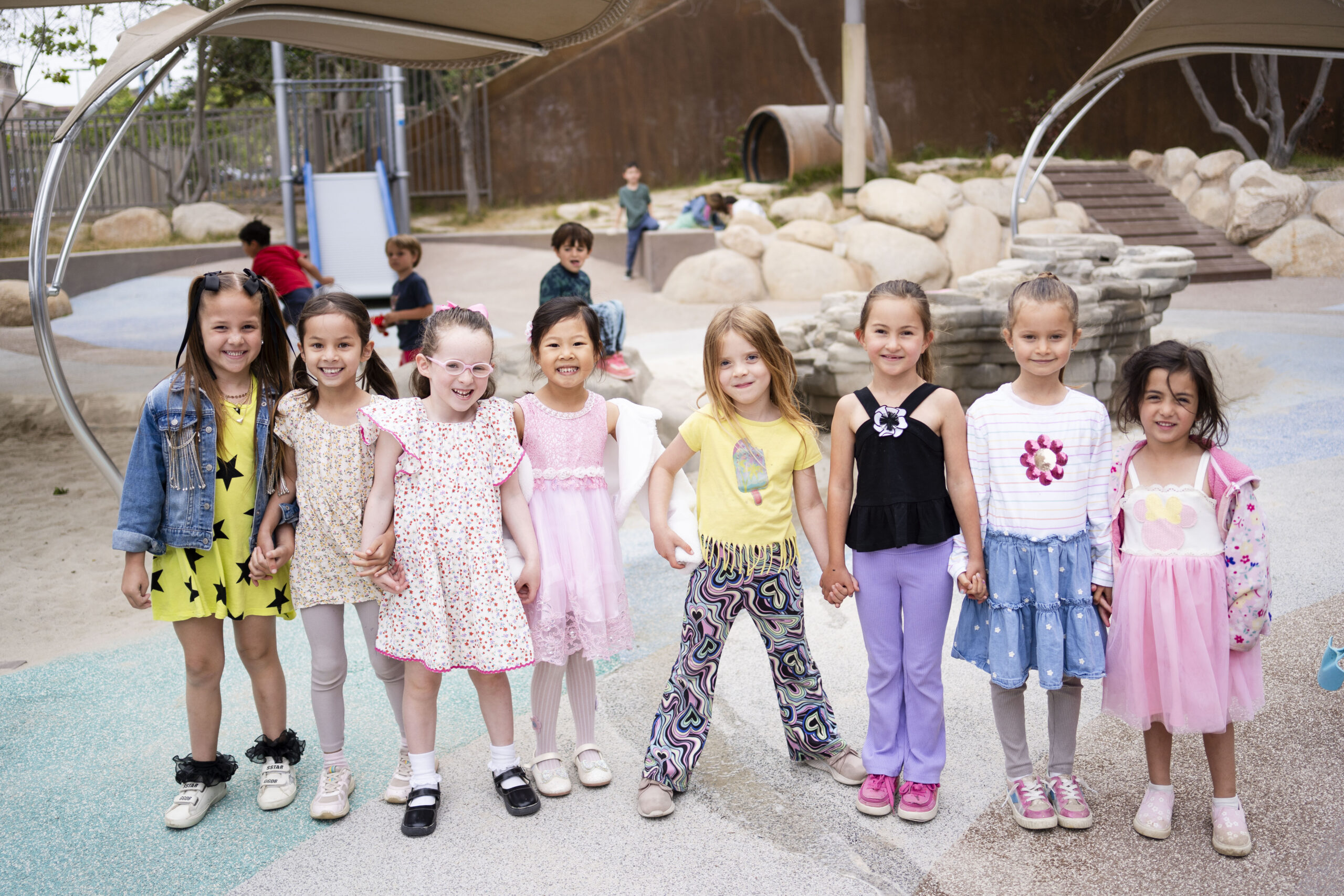 Preschool students posing and holding hands on the playground