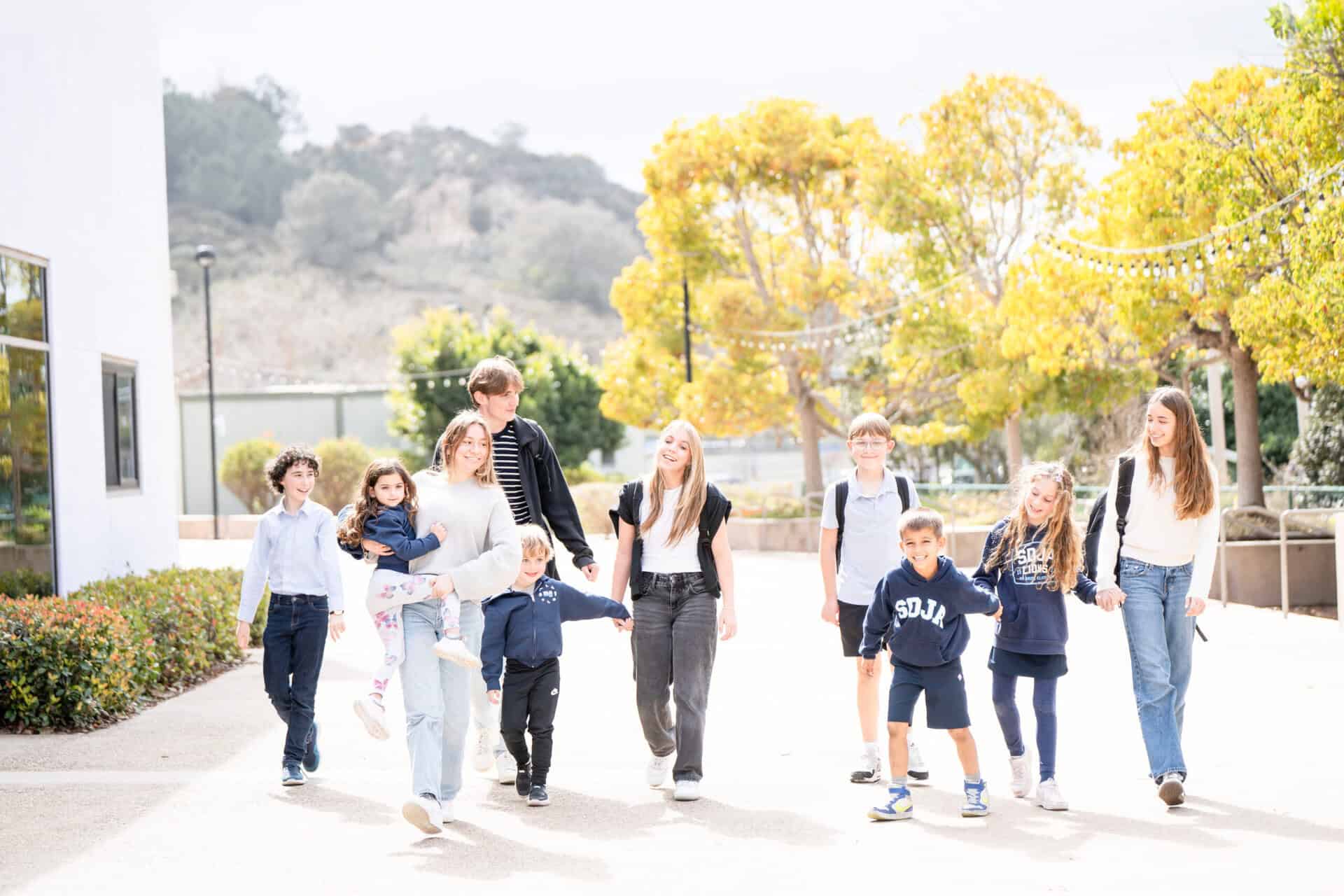 Students of mixed ages walking down a pathway on the SDJA campus.