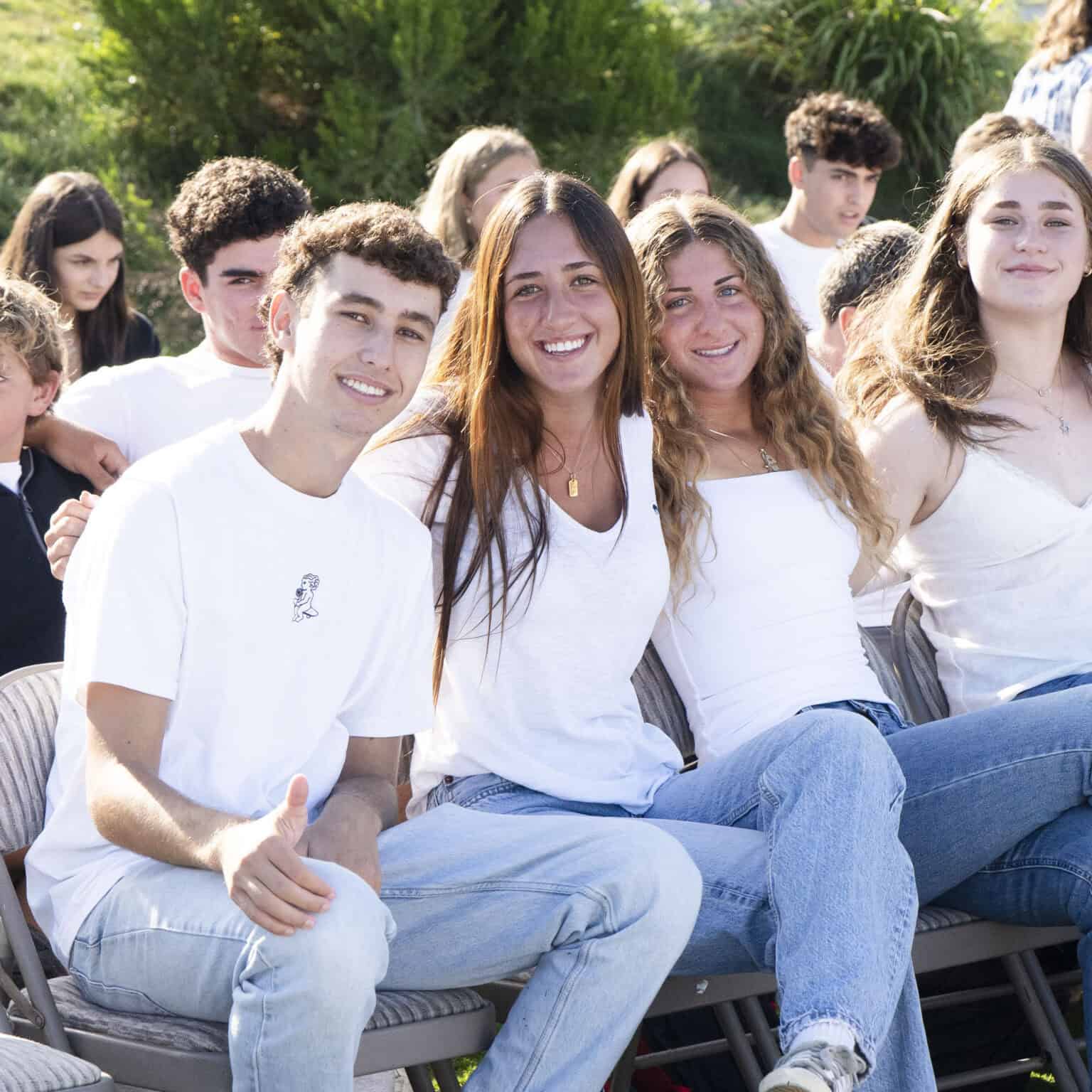 Three students in white tops and blue jeans smiling