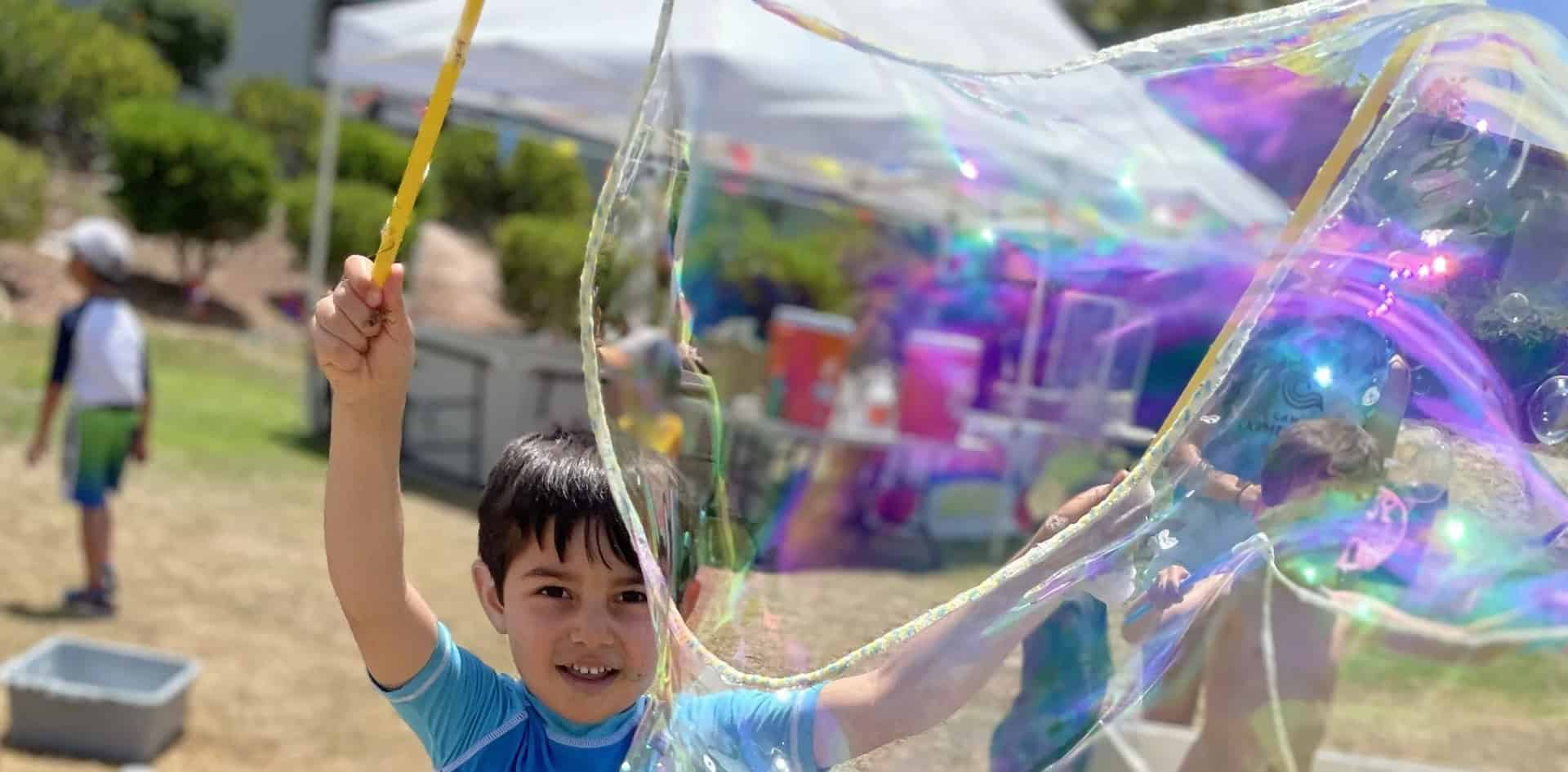 A boy making large bubbles outdoors