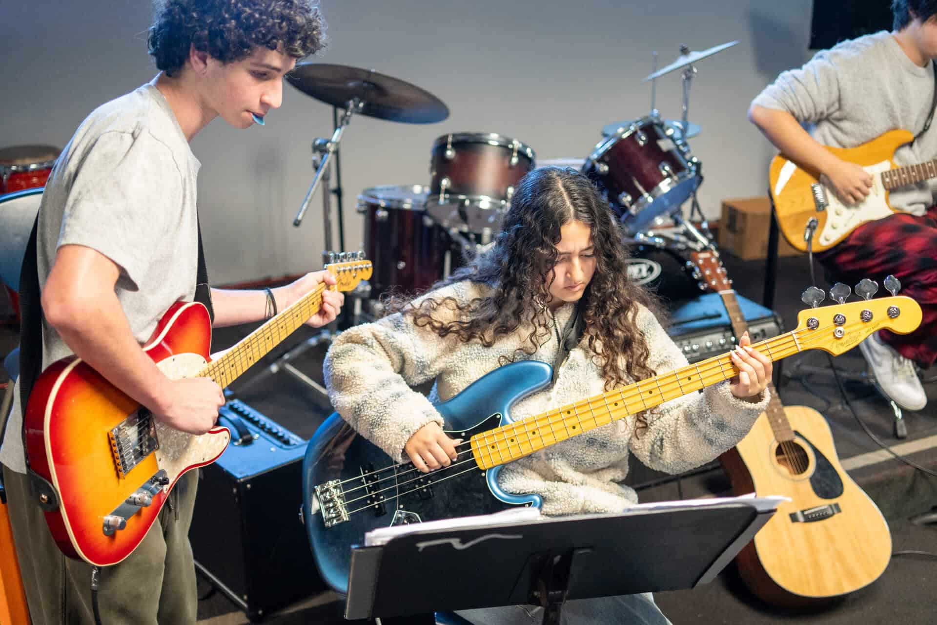 Students during band practice, holding guitars as basses