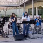 Upper school students performing music outdoors, featuring vocals, guitar, and keyboard