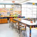 Lower School art classroom, featuring bright colors, hanging artwork, and painted tables and chairs.