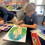 Lower school student working on a creative self-portrait painting.