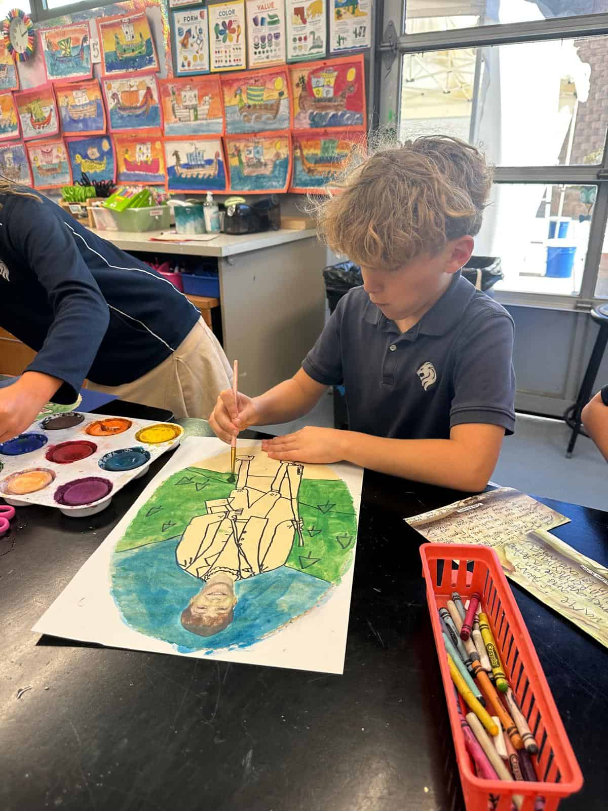 Lower school student working on a creative self-portrait painting.