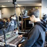 Students controlling audio and visuals through a mixing board at an SDJA parent presentation and conversation event