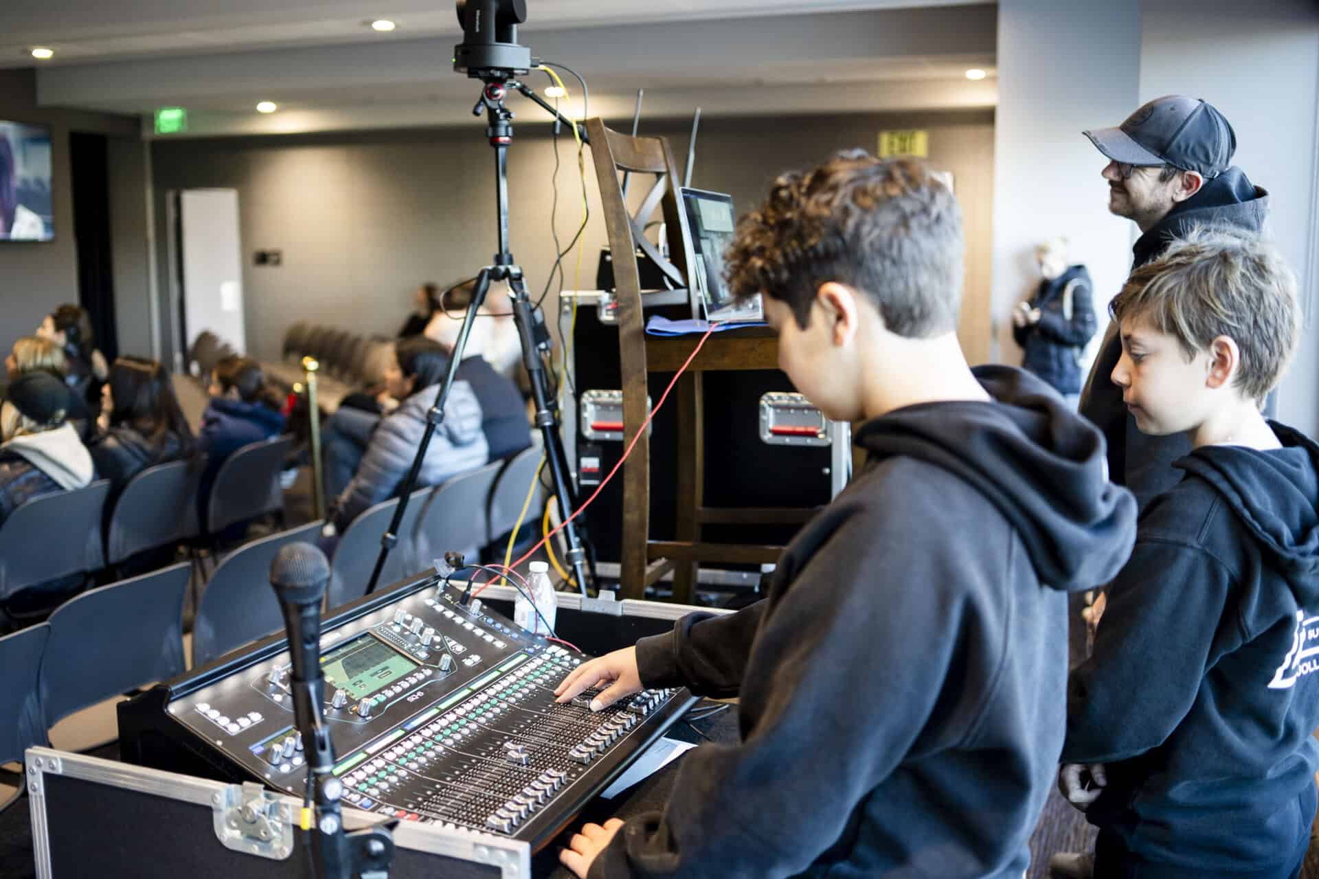 Students controlling audio and visuals through a mixing board at an SDJA parent presentation and conversation event