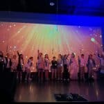 Lower school students performing on stage with lighting effects