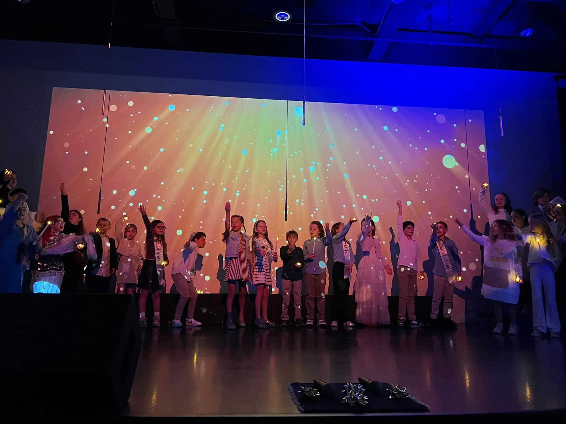 Lower school students performing on stage with lighting effects