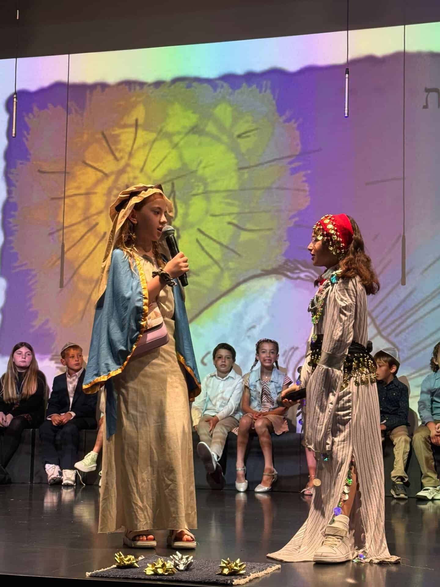 Students in costume on stage during a lower school performance