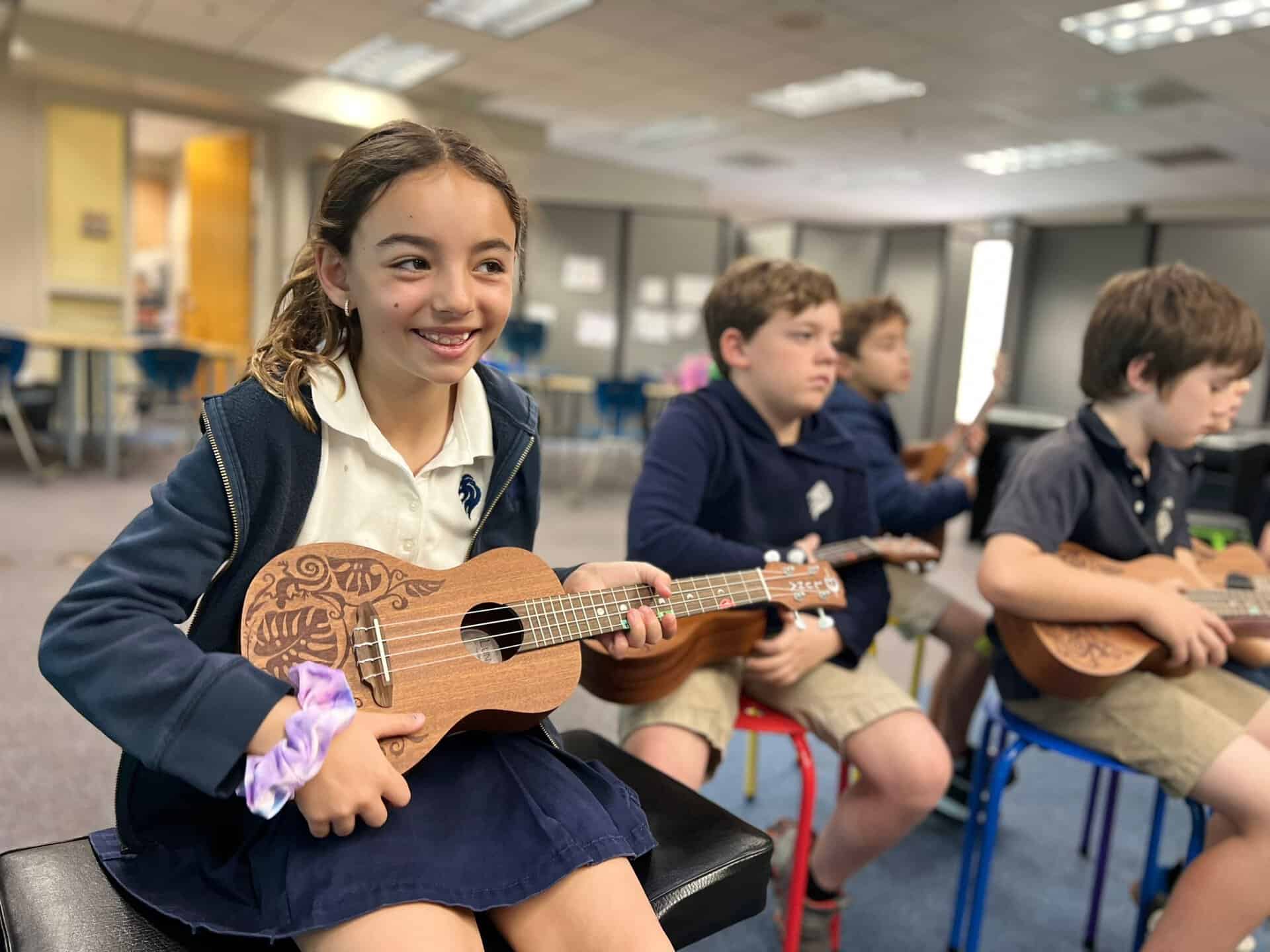 Lower school student smiles while holding a ukulele