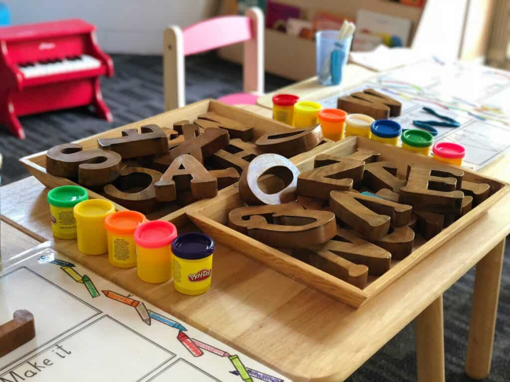 Block letters and play-doh sitting on a preschool desk