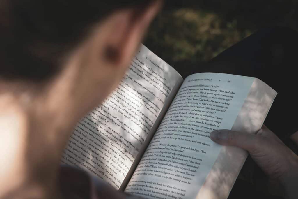 Person reading an open book outdoors