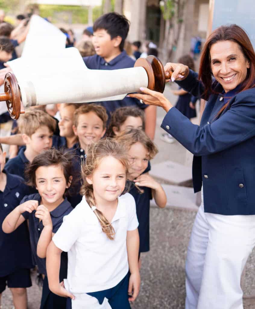 SDJA students walking underneath a rolled out Torah scroll