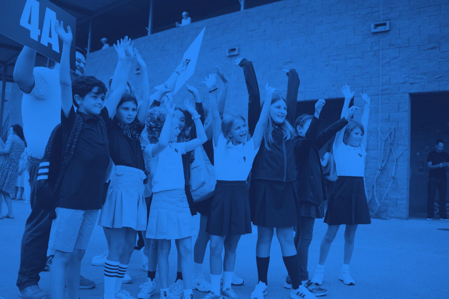 Students standing in a group on the SDJA campus, with their arms in the air.