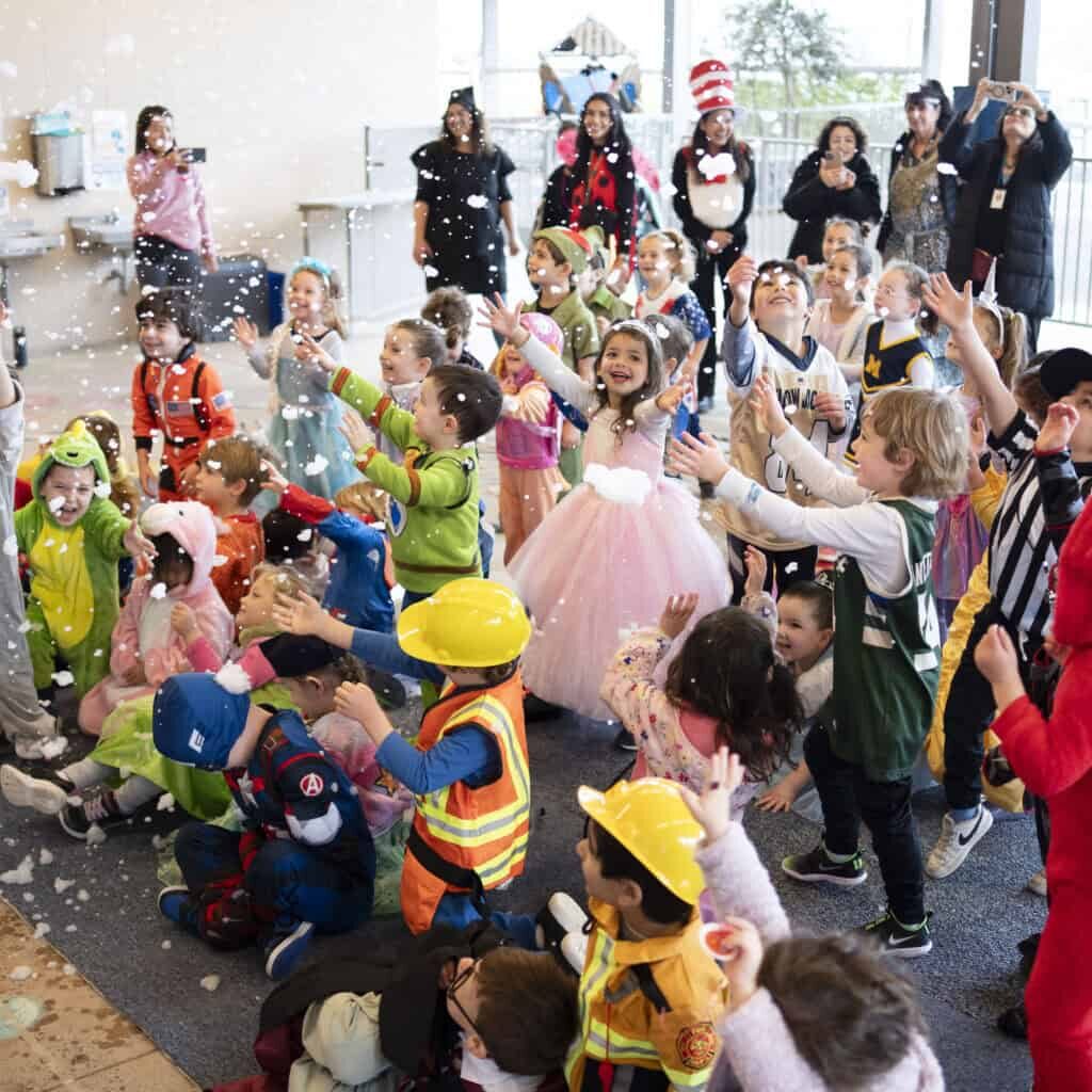 Preschoolers in costumes for Purim, playing with bubbles