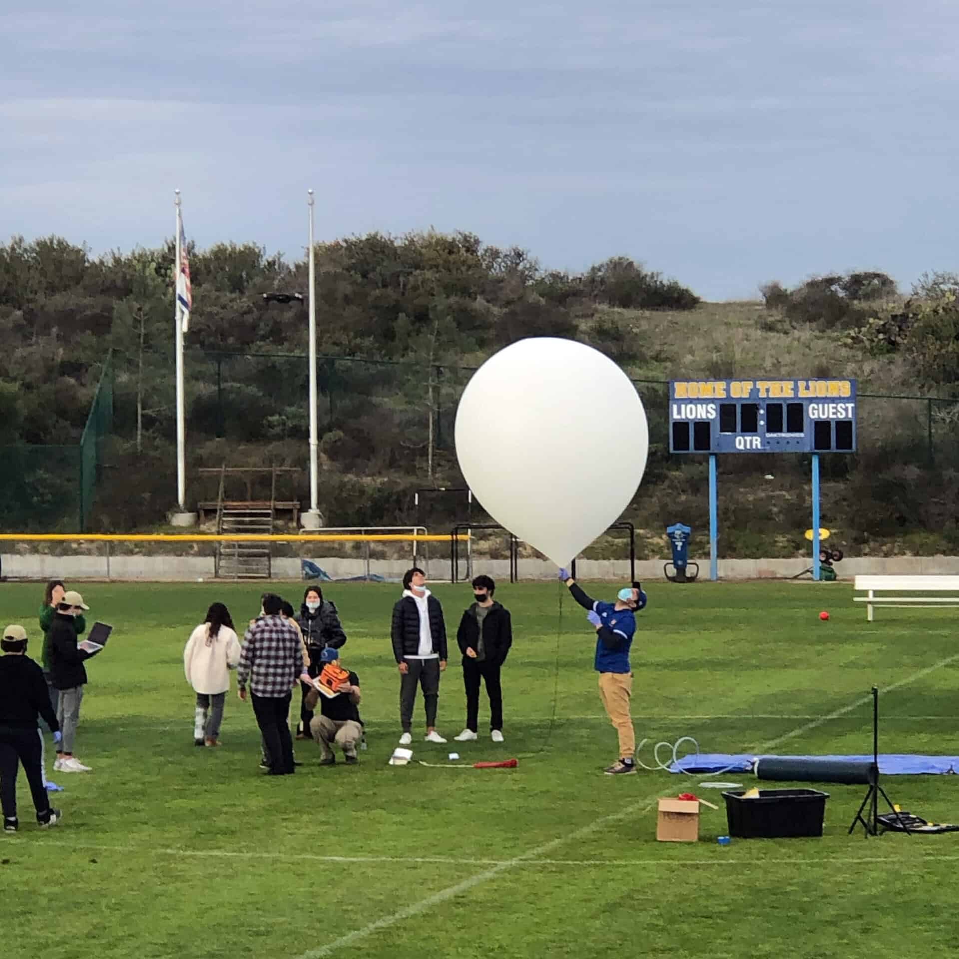 Students on the SDJA football field filling a large balloon to launch for an experiment.