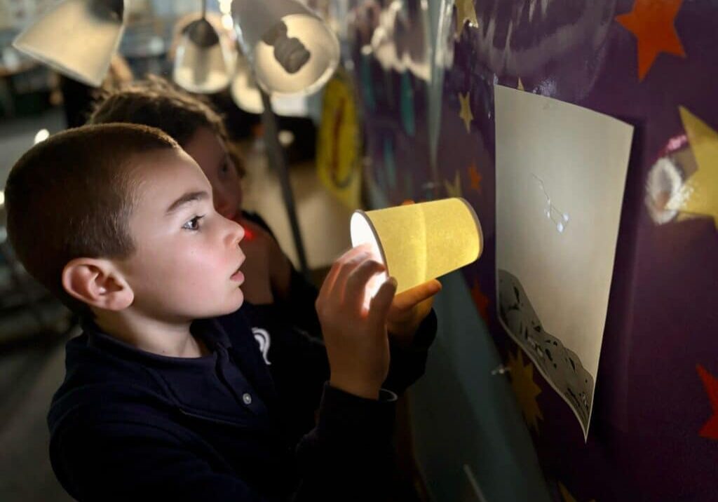 Elementary school student doing a science project with light projection